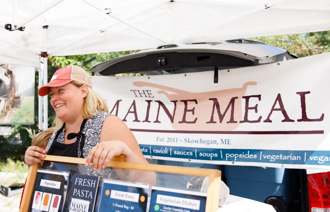 Kelly LaCasse at the Belfast farmers market beside The Maine Meal banner