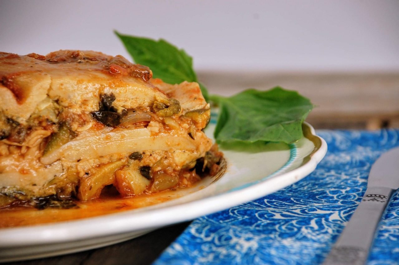 Vegetable lasagna on a plate with fresh basil