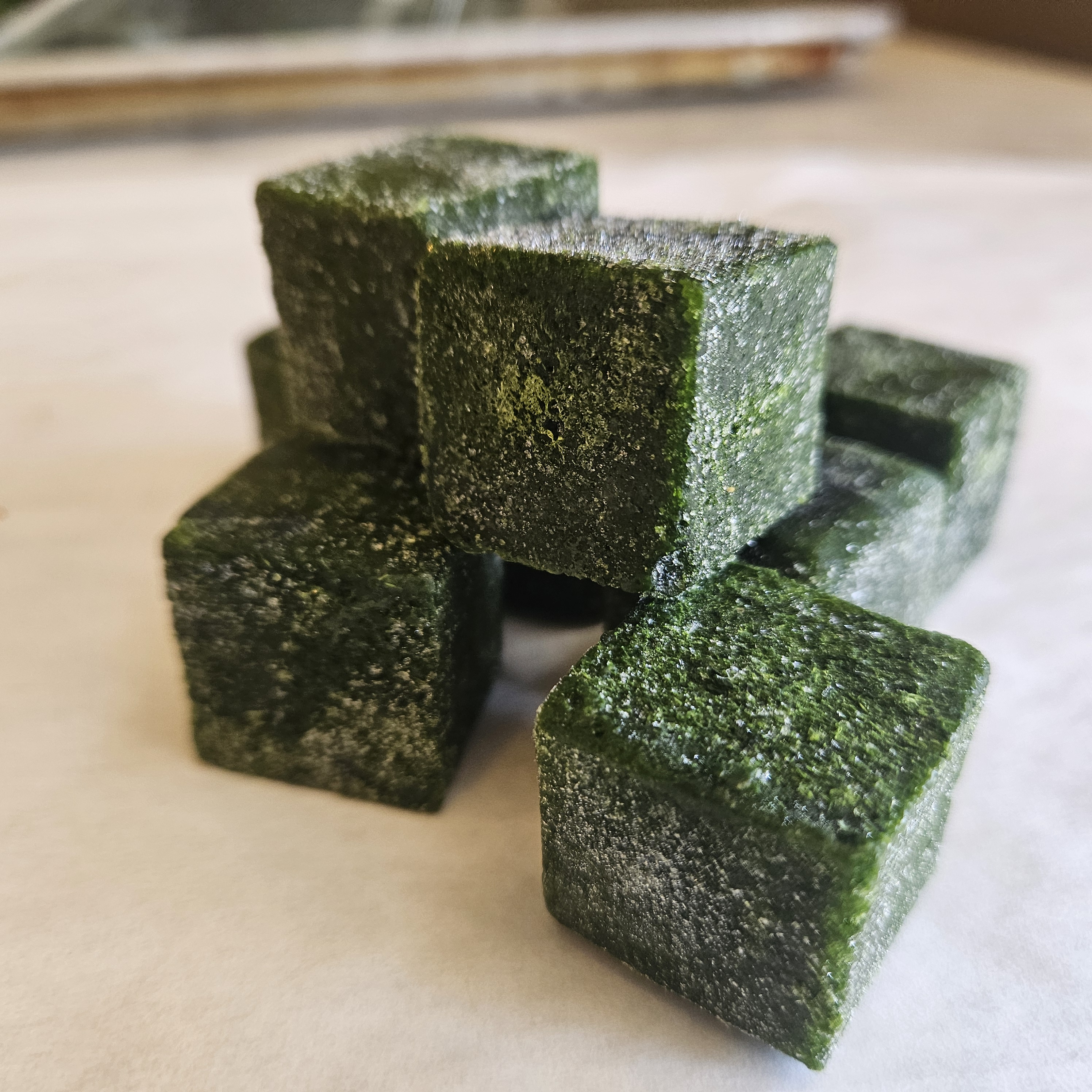 Frozen spinach cubes stacked on parchment