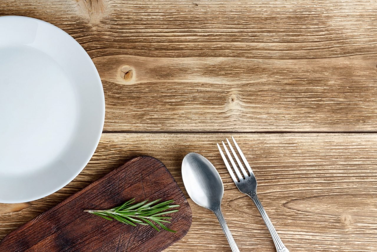 A plate, cutting board and rosemary on a wooden table